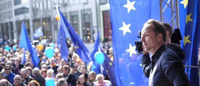 Ustanovitelj iniciative "Pulse of Europe" Daniel Röder, obkrožen z modrimi baloni in zastavami pri shodu za Evropo v Frankfurtu na Majni.