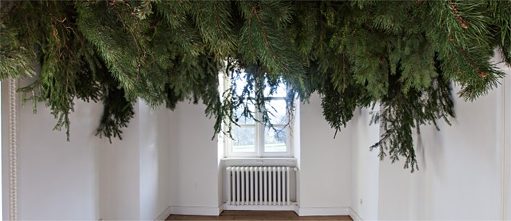 Photo d'une installation artistique. Une chambre dont le plafond est couvert de branches de sapin.