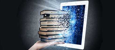 Eine Hand mit einem Bücherstapel vor einem Tablet