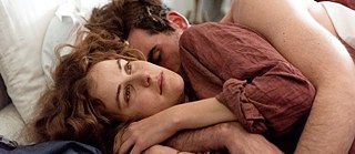 Paula, Szenenbild: eine Frau und ein Mann liegen in enger Umarmung im Bett