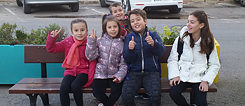 Die neunjährige Elena gemeinsam mit ihren Weggefährten auf der Bank vor ihrer Schule.