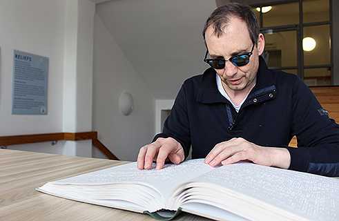 Stefan Debus leyendo un libro en braille en la Biblioteca central alemana para ciegos.