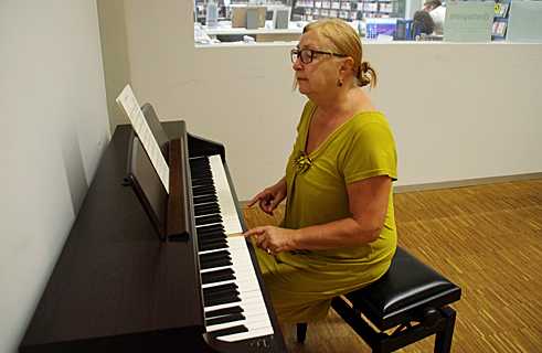En el piano eléctrico de la sala de música, Renate busca los tonos de las canciones. 