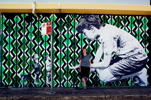 Die Street Art Künstlerin Mandy Schöne-Salter vor ihrem Werk ‘Imagine‘ (2015), das im Rahmen des Avalon Art Carnival 2015 entstand. Es zeigt die Fantasiewelten, die Kinder während des Spielens entdecken.