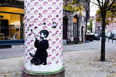 Mandy Schöne-Salter designed and installed a street art mural for a round advertising pole in Nürnberg (Germany) called 'Litfaßsäule'. The mural consists of a two layered stencil as a background pattern and a couple of paste-up photographs on top.
