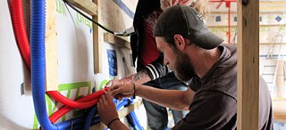 Martin, conseillé par son père, installe les arrivées d'eau.