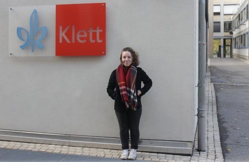 Élève devant une mure sur laquelle s'affiche le panneau d'entreprise Klett