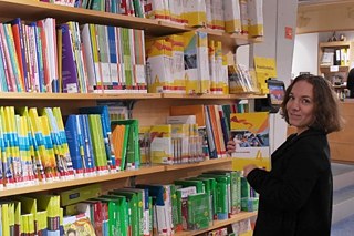 Élève devant une bibliotheque, dans laquelle se trouvent beacoup de livres d'entreprise Klett