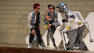 Die drei Hauptfiguren der Kinderuni, der Professor, seine Assistentin und der Roboter, auf der Bühne