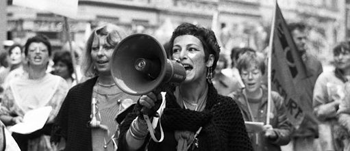 Manifestation de femmes : la femme au centre de l’image en noir et blanc parle dans un mégaphone