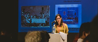 Lilia Schwarcz mostra slide com pintura de Jean-Baptiste Debret (A Brazilian dinner, 1827), à esquerda, e de François Désiré Roulin (Le diner à Ste. Marthe, 1823), à direita