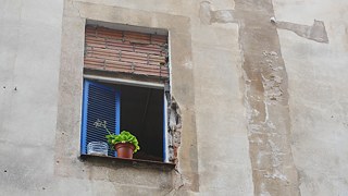 Fenêtre à moitié murée dans une maison squattée