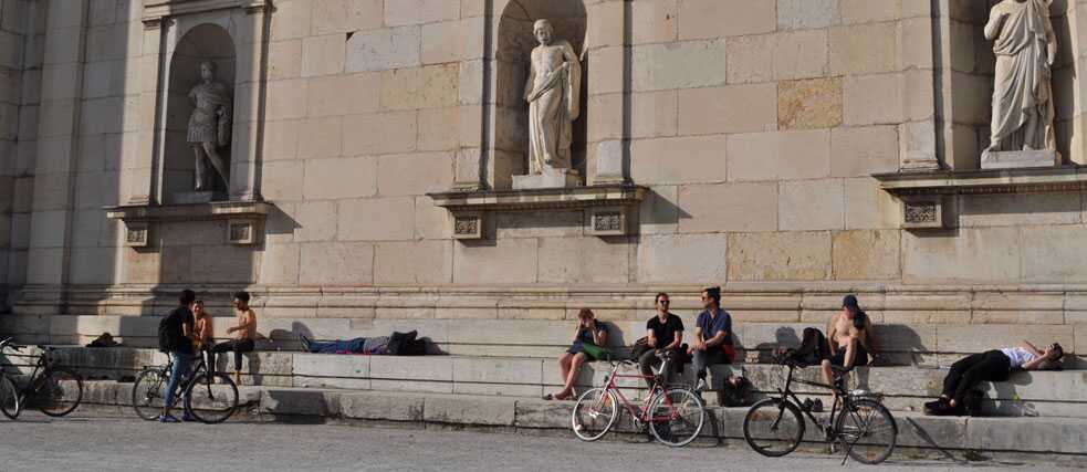 Eine Gruppe von Menschen entspannt auf dem Königsplatz in München.