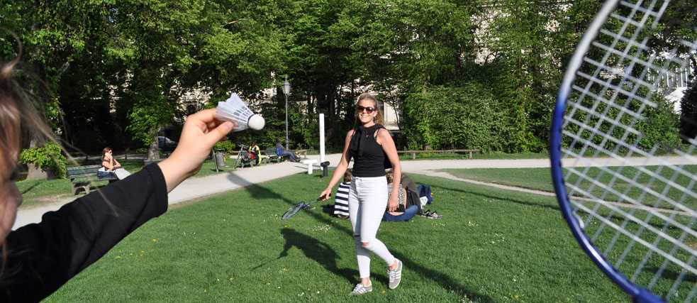 Ein Mädchen und eine Frau spielen zusammen Federball in der Sonne.