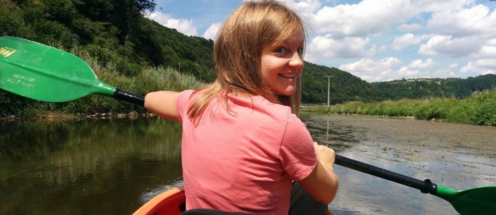 A young woman is canoeing down a river.