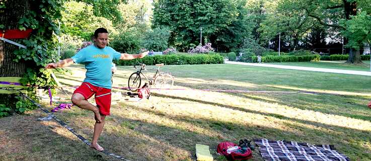 A man balancing on a slackline in a park.