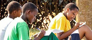 Drei Mädchen sitzen auf dem Rasen und schreiben