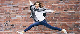 Een jonge vrouw springt in de lucht. 