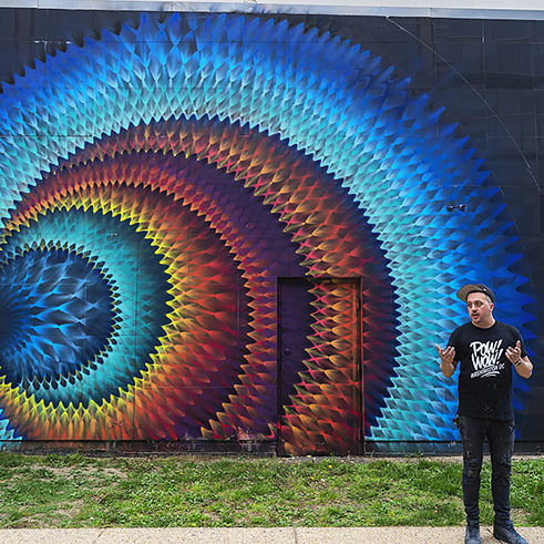 Kelly Towles speaking in front of the POW! WOW! DC 2016 mural of HOXXOH