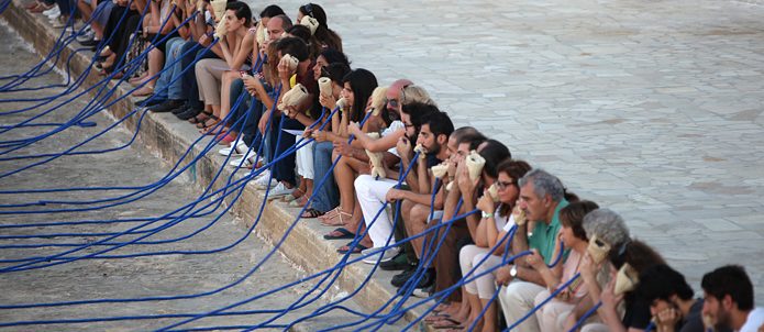 Menschen sitzen in einer Reihe und nehmen an einer Kunstperformance teil