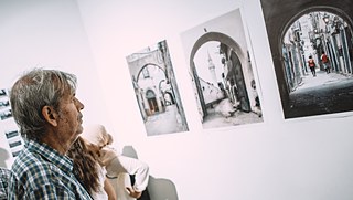 A visitor of the exhibition „Portion of Libya“ looking at pictures of Heba Alshibani