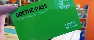 Eine Hand hält den Goethe Kultur-Pass, eine kleine grüne Karte. 