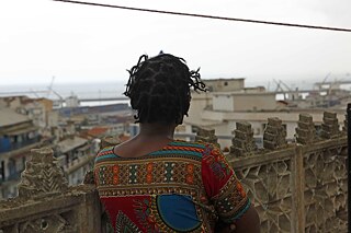 A woman, Aicha looking out on the port from a terrace in Algiers.
