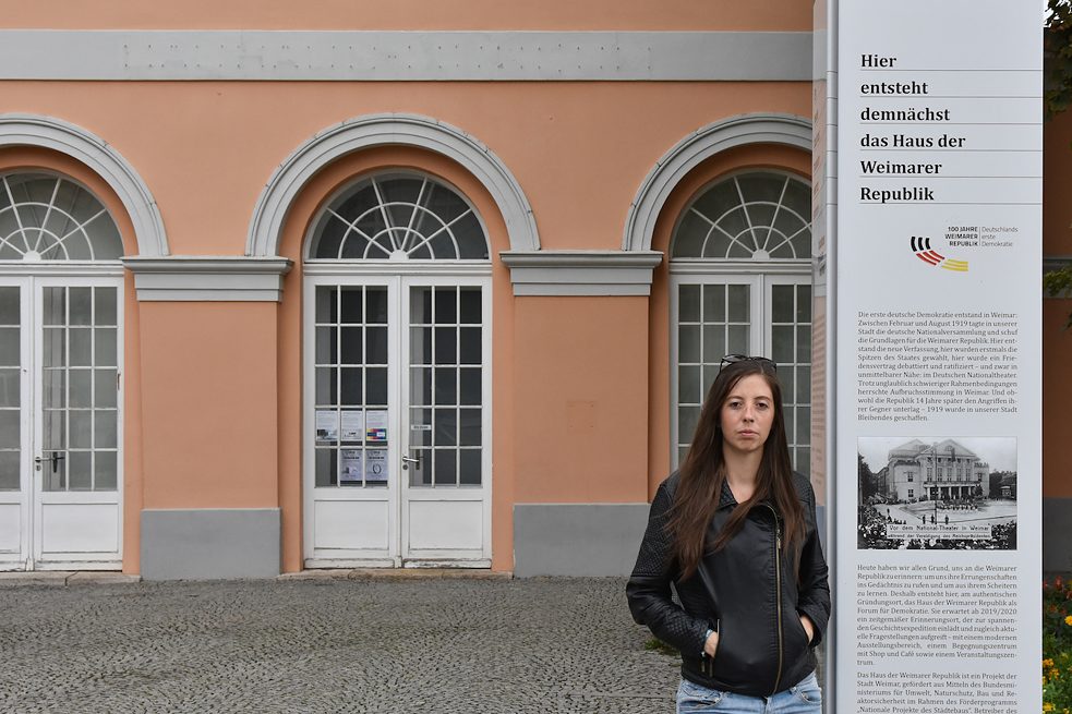 <b>Marie-Louise Stille</b>, argentinisch-deutsche Kultur- und Theaterproduzentin, Bauhaus-Universität Weimar: Das Bauhaus hat mich dazu gebracht, mir bei jedem neuen Projekt die Frage nach der Funktionalität zu stellen. Es hat mich gelehrt, Schlichtheit nicht als etwas Einfaches zu begreifen, sondern als einen Weg, der sich aus vielen Suchetappen zusammensetzt, um zu einem bestimmten Ziel zu gelangen. Durch mein Studium habe ich Zugang zu einer Tradition erhalten, die den Stellenwert und die Funktion der Künste kritisch hinterfragt.  <br><br>  <b>Foto:</b> Vor dem alten Bauhaus-Museum. Das Gebäude, aus dem das Haus der Weimarer Republik entstehen soll, lässt mich an die Beziehung zwischen dem Bauhaus und der deutschen Demokratie denken, und daran, wie das Bauhaus die Freiheit seiner Studierenden durch das Experimentieren fördert.