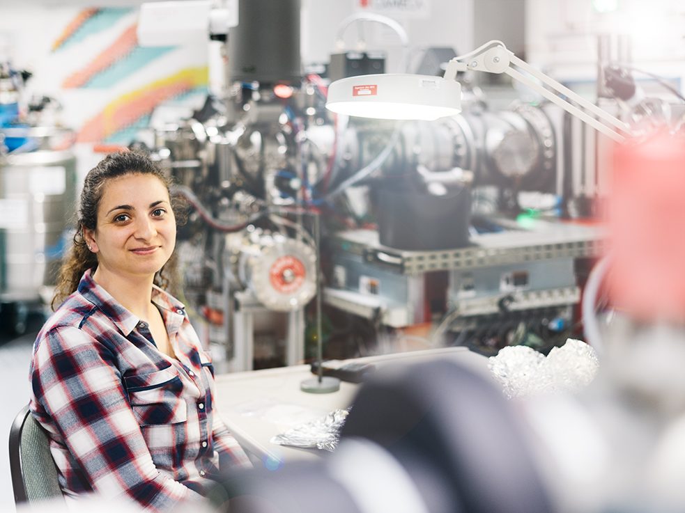 <b>Marta Codeço im Labor des GFZ Potsdam. Im Hintergrund das Sekundärionen-Massenspektrometer (SIMS) </b><br><br>„Frauen in der Wissenschaft, das ist manchmal immer noch ein Abenteuer.“ Marta ist sehr zufrieden mit ihrer Doktorandenstelle in Deutschland. Dass es Frauen in der Wissenschaft nicht immer leicht haben, möchte sie dennoch noch einmal gesagt haben. „Ich glaube, dass es heute schon weniger üblich ist als früher, aber auch mir sind in meiner Laufbahn einige Leute mit Macho-Allüren über den Weg gelaufen, für die Frauen nichts in der Geologie verloren haben, insbesondere in Fachgebieten wie der geologischen Kartografie und in der Feldforschung.“