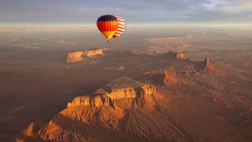 Seite an Seite schweben die Heißluftballons in den Nationalfarben Deutschlands und der USA über das Monument Valley. 