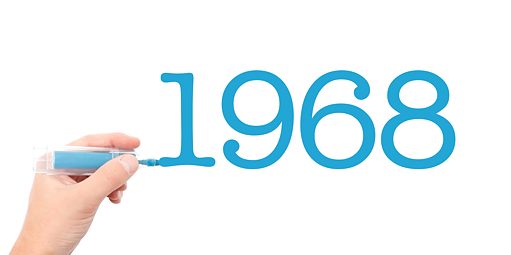 1968“ in Zahlen in blau wird von einer Hand mit blauen Stift auf weißen Hintergrund geschrieben