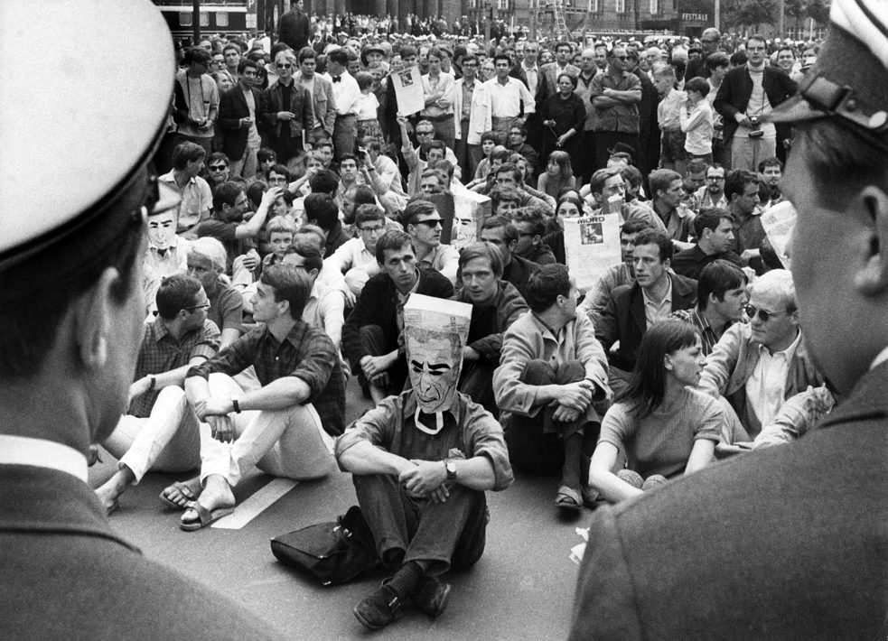 Demonstranten im Sitzstreik werden am 02.06.1967 vor dem Rathaus Schöneberg in Berlin von der Polizei beobachtet. Die Demonstranten protestierten gegen den Besuch des persischen Herrschers Schah Reza Pahlevi. Bei den Zusammenstößen zwischen Demonstranten und Polizei die später am Tag folgten wurde der Student Benno Ohnesorg erschossen.