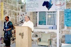 يوسف قوس (يسار) وفيصل الحسيني، الممثل السابق لمنظمة التحرير الفلسطينية في القدس، يقفان في غرفة جدرانها حجرية، في افتتاح المركز الاجتماعي، القدس ١٩٩٦.