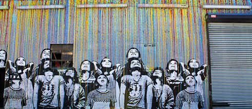 Graffiti, jossa eri taustaiset lapset katsovat ylös taivaalle.