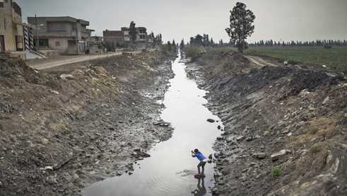One of the children in Bahr Al-Tibn washing himself in sewage water. Detail from "We, the Living Dead, 2018"