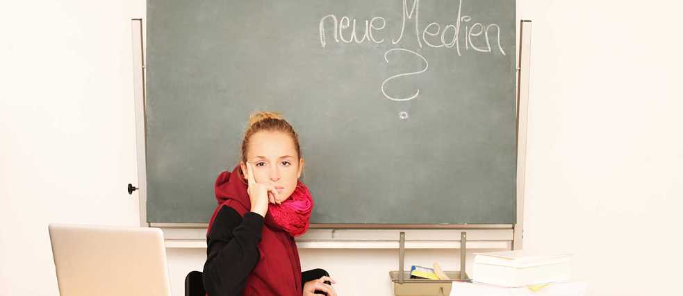 Mädchen im Klassenzimmer mit Tafel und Laptop