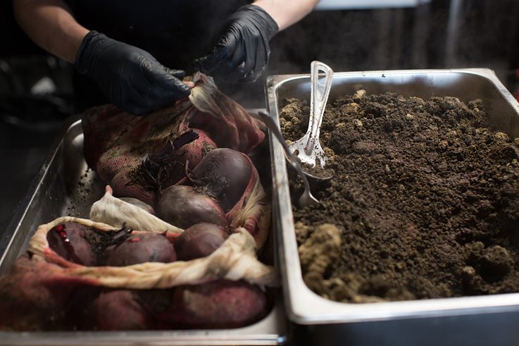 Sous chef Maxime Gnojczak uncovers the beetroot which have been baking in soil