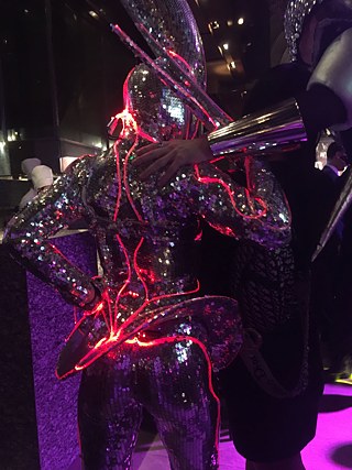 In futuristisch angehauchtem Look verkleidete Wesen auf Stelzen