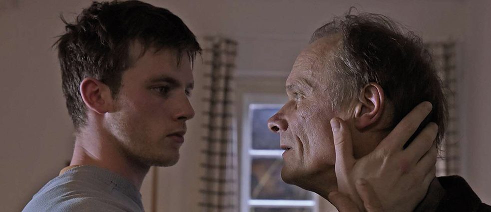 Simon stands close to Johannes and fondles his face. 