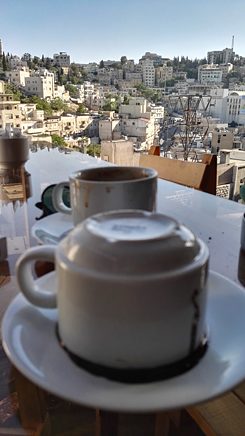 Two empty coffee cups on a terrace overlooking the city of Amman.
