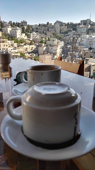 كوبان فارغان من القهوة على شرفة تطل على مدينة عمان.