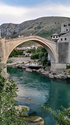 A tall old bridge over a river in Mostar, a small town.				