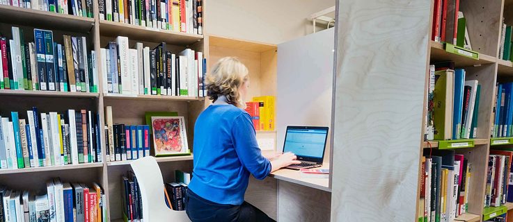 A woman sitting in the study area of the library with a laptop.