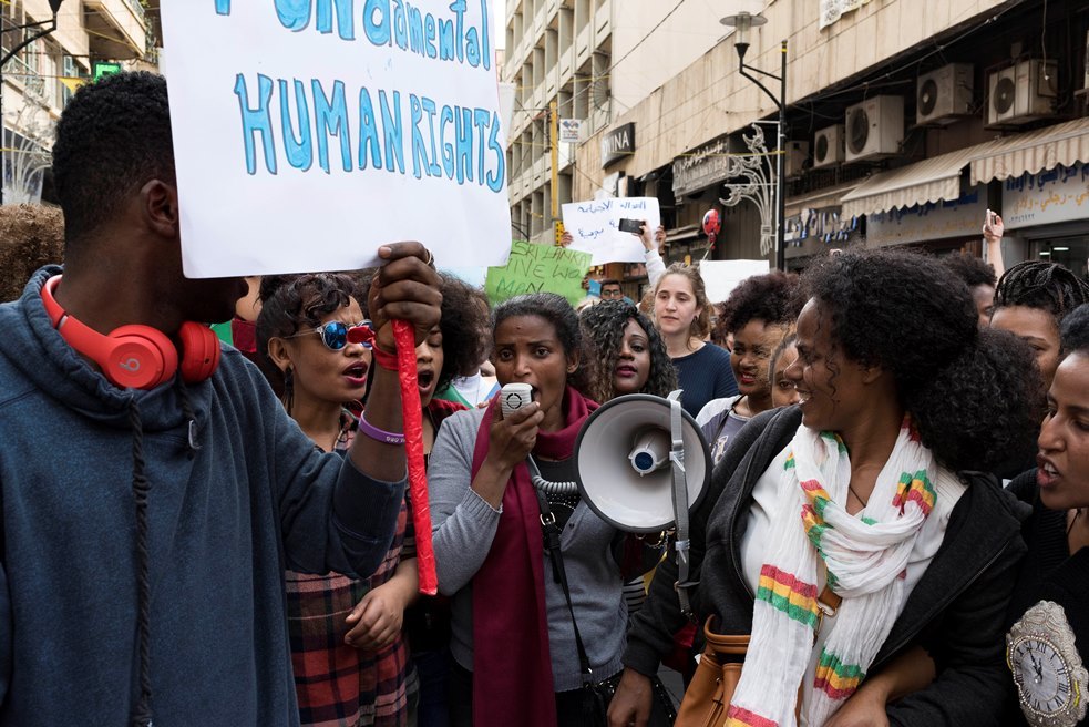 Des manifestants à Beyrouth. Au centre de la photo, une femme avec un haut-parleur, tandis que d'autres femmes la regardent et qu'un homme tient une pancarte appelant aux droits humains.