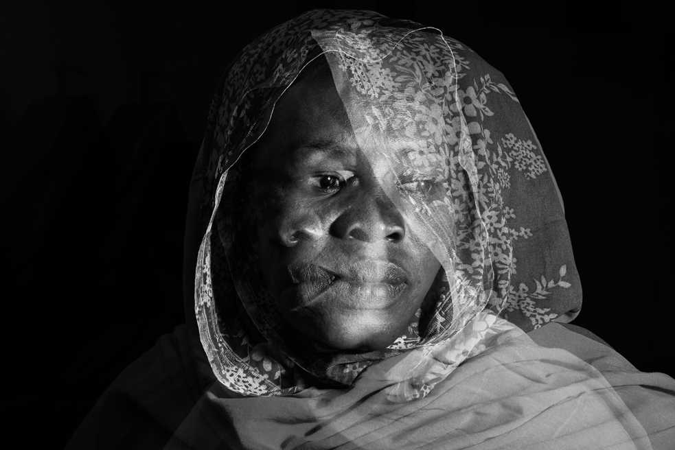 Black and white close-up of a women's face, a silhouette of her face on her cheek looking to the side depicting internal and external conflict.