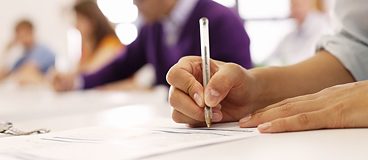 A hand holding a pen writing answers in a test.