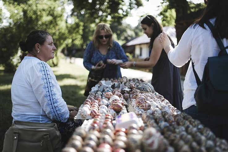 Eine Frau verkauft bemalte Eier an amerikanische Touristinnen. 