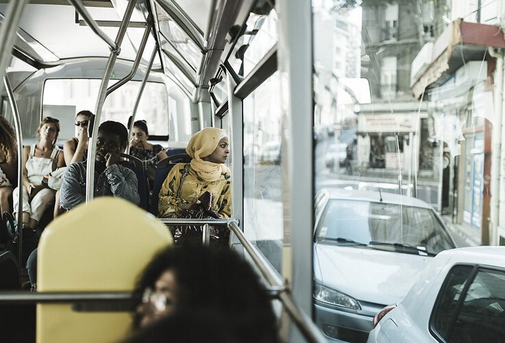 A woman watches the city from a bus window.