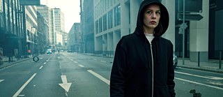 Jana Liekam (Paula Beer) clothed in a black hoody tries not to get recognized in the streets of Frankfurt...
