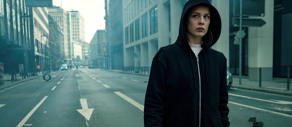 Jana Liekam (Paula Beer) clothed in a black hoody tries not to get recognized in the streets of Frankfurt...